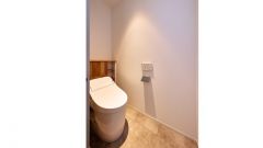 コンパクトなローシルエットの一体型トイレの背面には木調タイルのカウンター